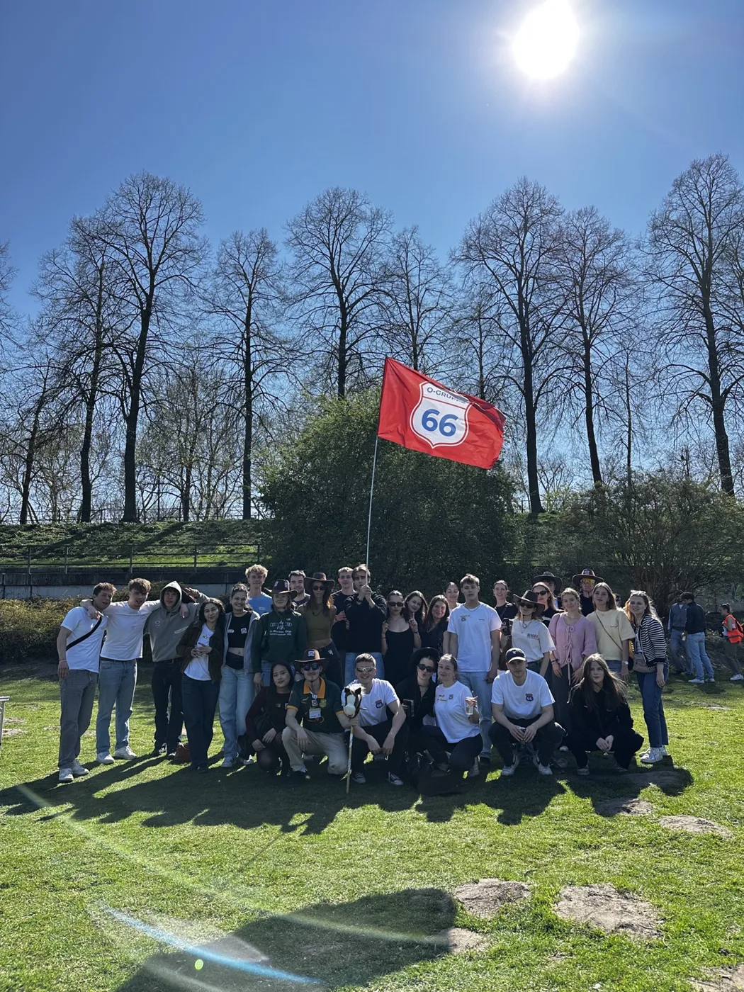 Gruppenfoto unter Bäumen mit der Flagge der O-Gruppe 66